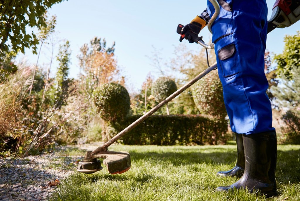 gardener-with-weedwacker-cutting-grass-garden.jpg